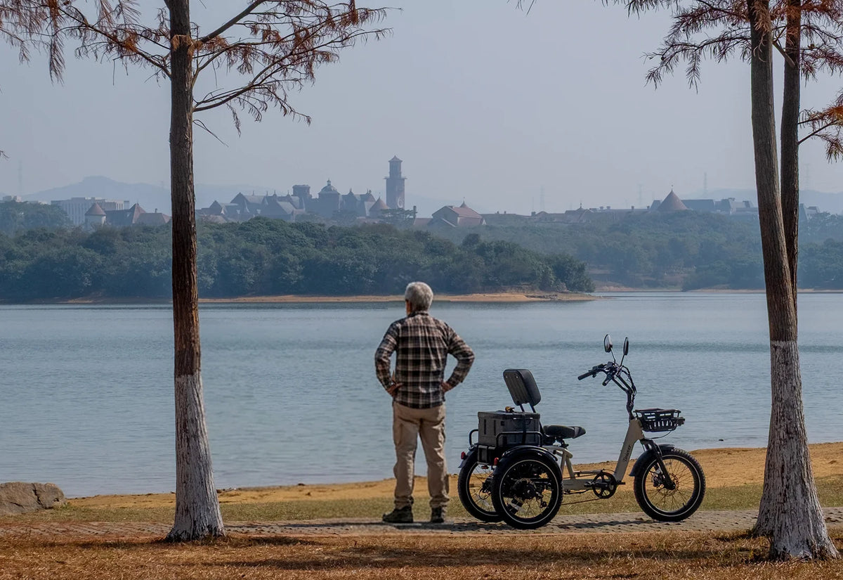 White Tiniover River electric trike parked beside a lake with a rear storage box and front basket